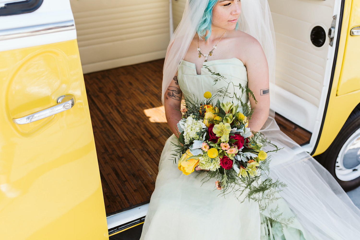 blue hair bride in strapless gown holding bright bouquet sits on floor of yellow vintage VW bus in Chattanooga Tennessee