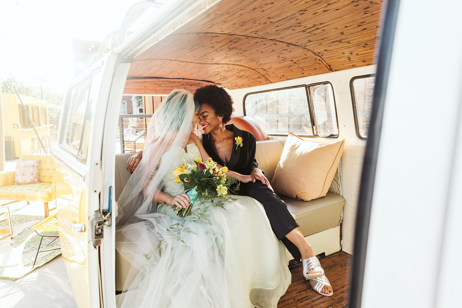 lesbian brides at LGBTQ wedding in Chattanooga styled shoot cuddle in back of vintage yellow Volkswagon bus at Moxy Hotel