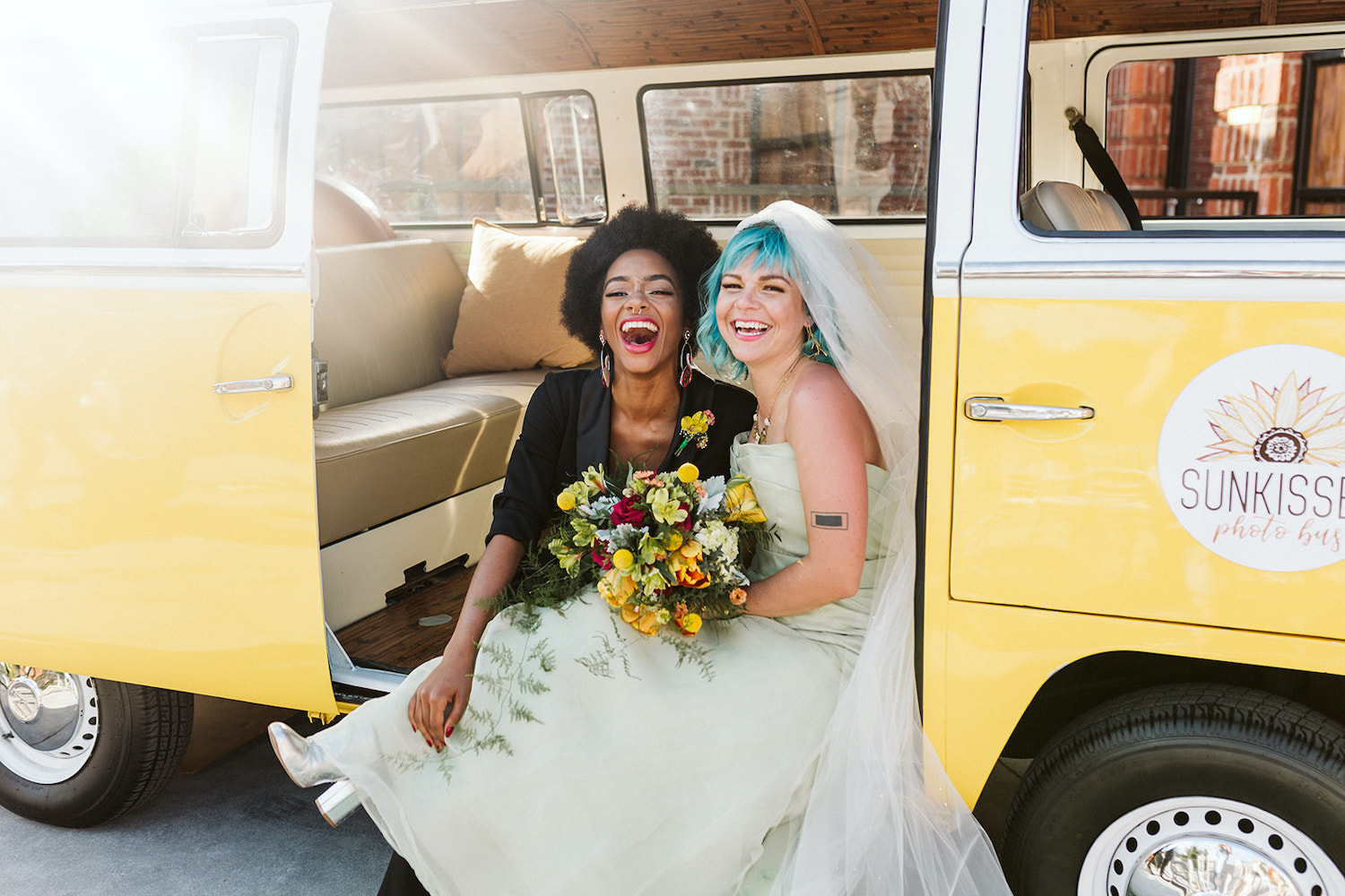 lesbian brides at LGBTQ wedding in Chattanooga styled shoot cuddle on running board of yellow Volkswagon bus at Moxy Hotel