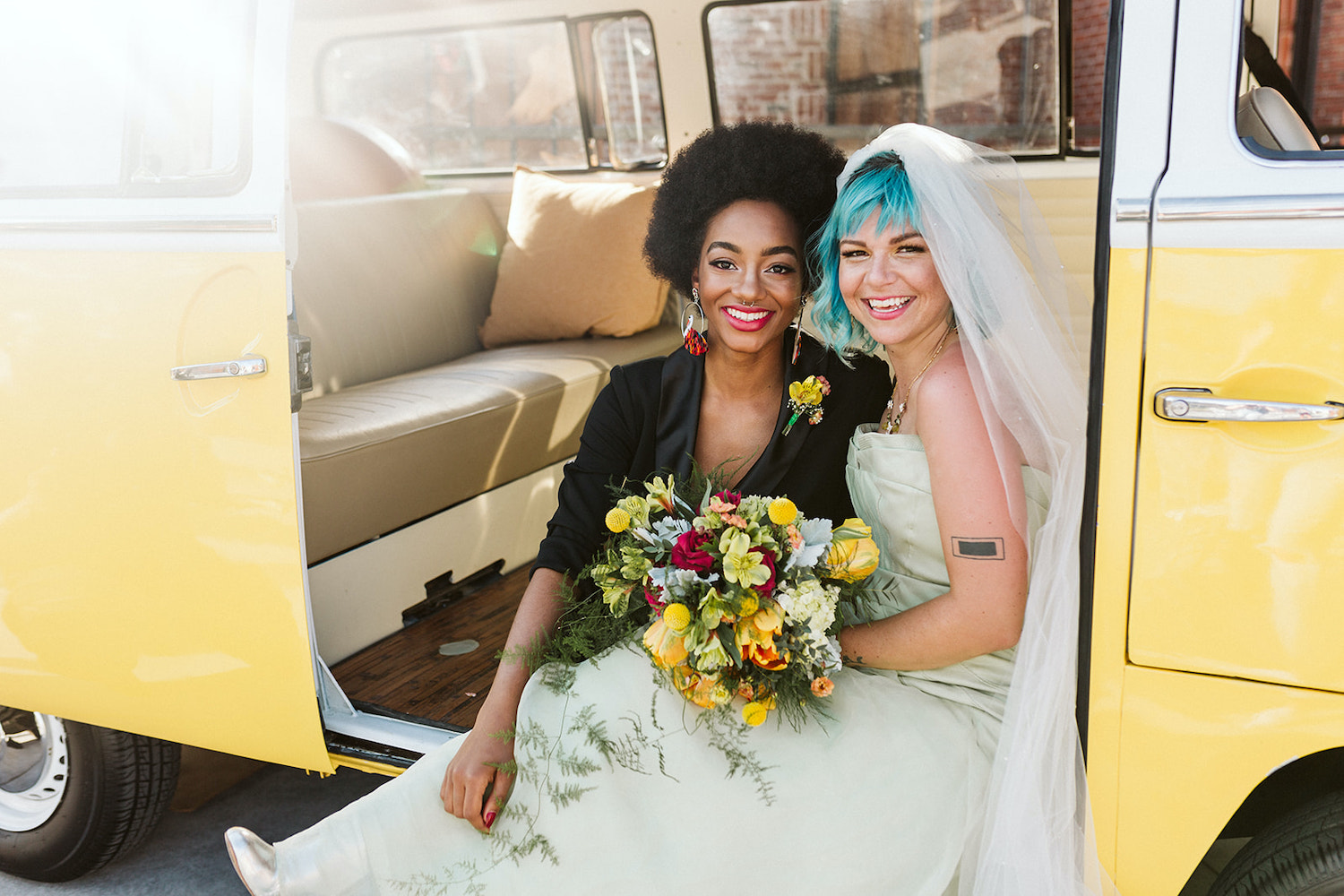 lesbian brides at LGBTQ wedding in Chattanooga styled shoot cuddle on running board of yellow Volkswagon bus at Moxy Hotel