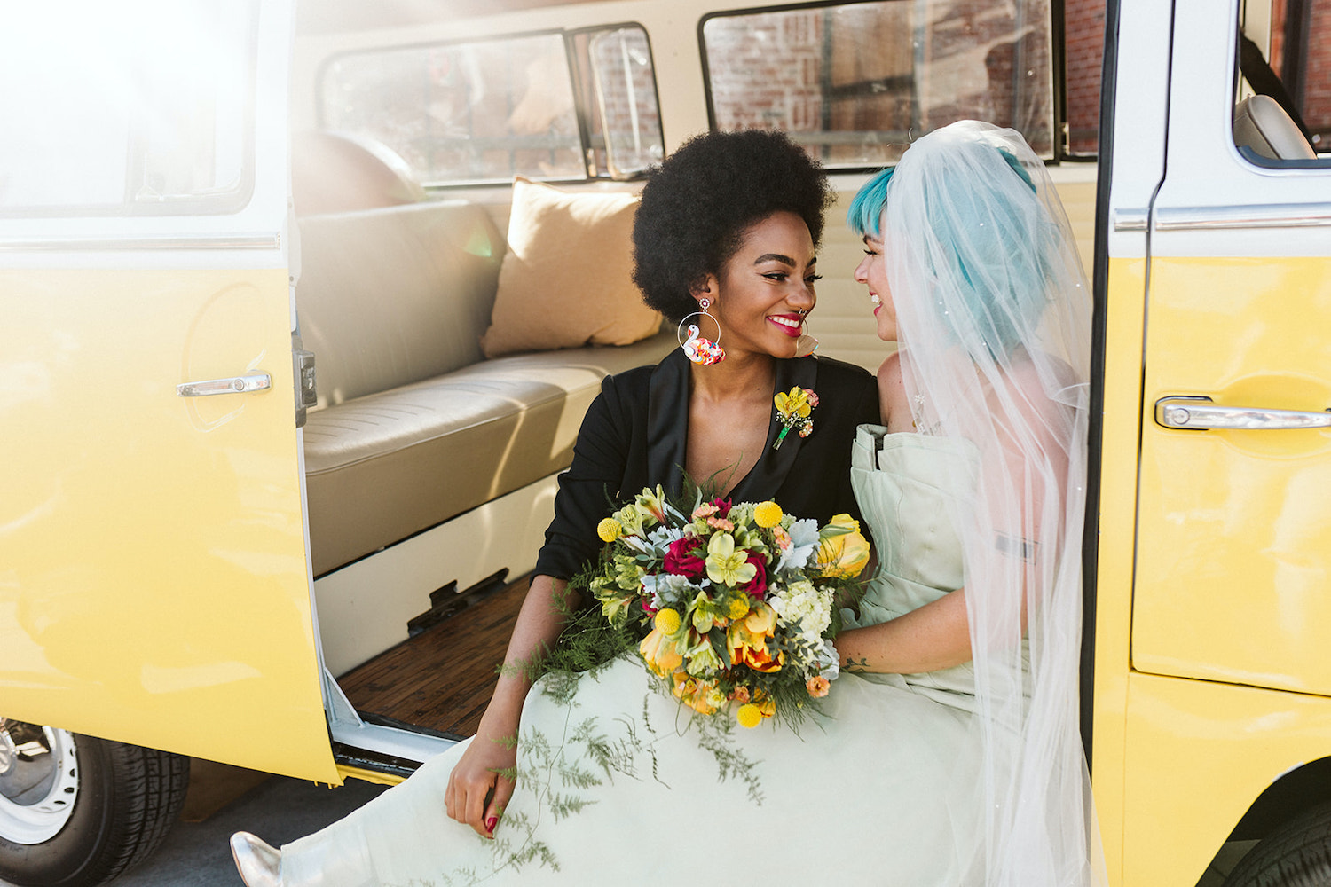 lesbian brides at LGBTQ wedding in Chattanooga styled shoot cuddle on running board of yellow Volkswagon bus at Moxy Hotel