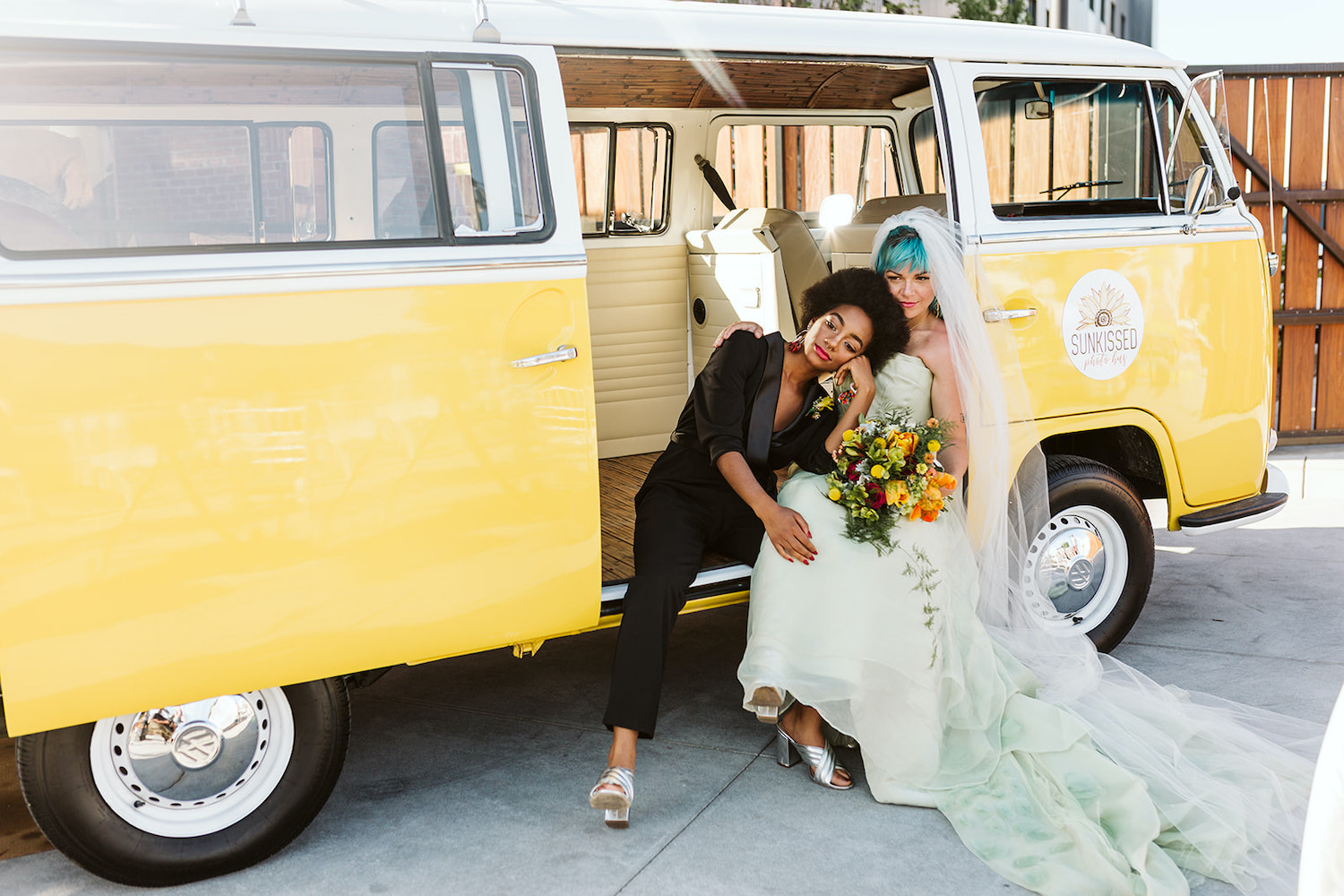 lesbian brides at LGBTQ wedding in Chattanooga styled shoot cuddle on running board of yellow Volkswagon bus at Moxy Hotel