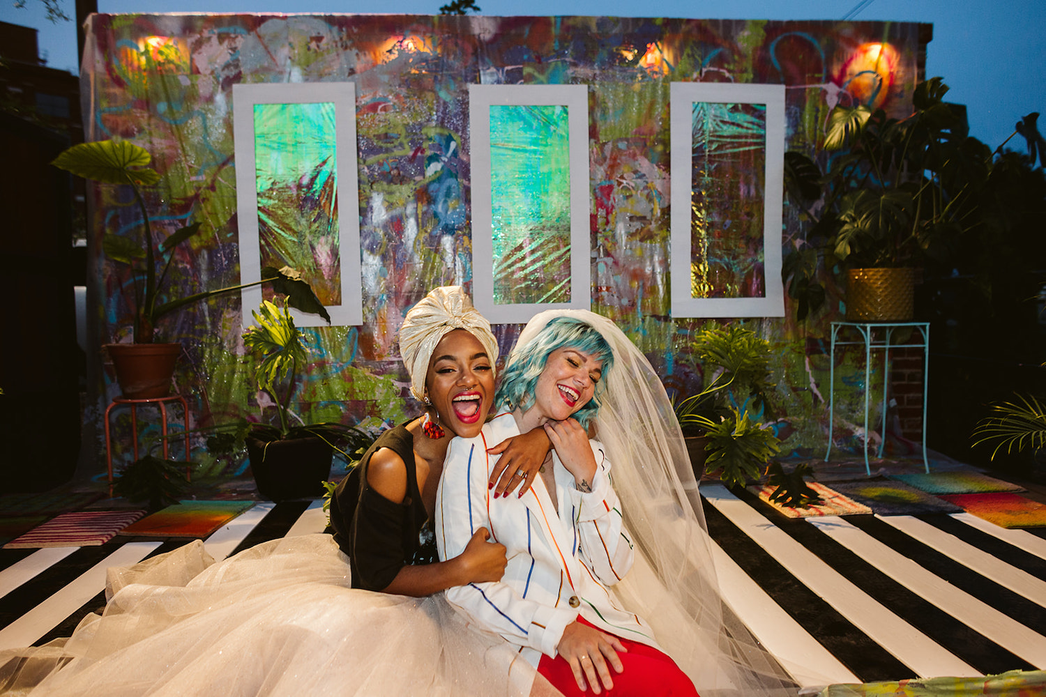 two brides snuggle and laugh on artistically painted platform for lesbian LGBTQ wedding in Chattanooga styled shoot