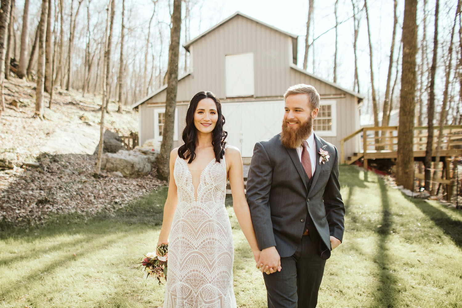 bride and groom hold hands and walk in the lawn in front of Oakleaf Cottage wedding