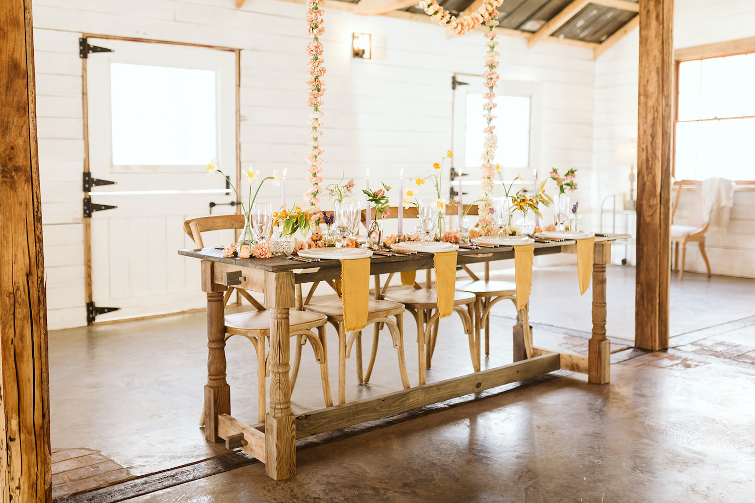 farm table with goldenrod napkins and simple table settings sits under pink carnation garland at Oakleaf Cottage