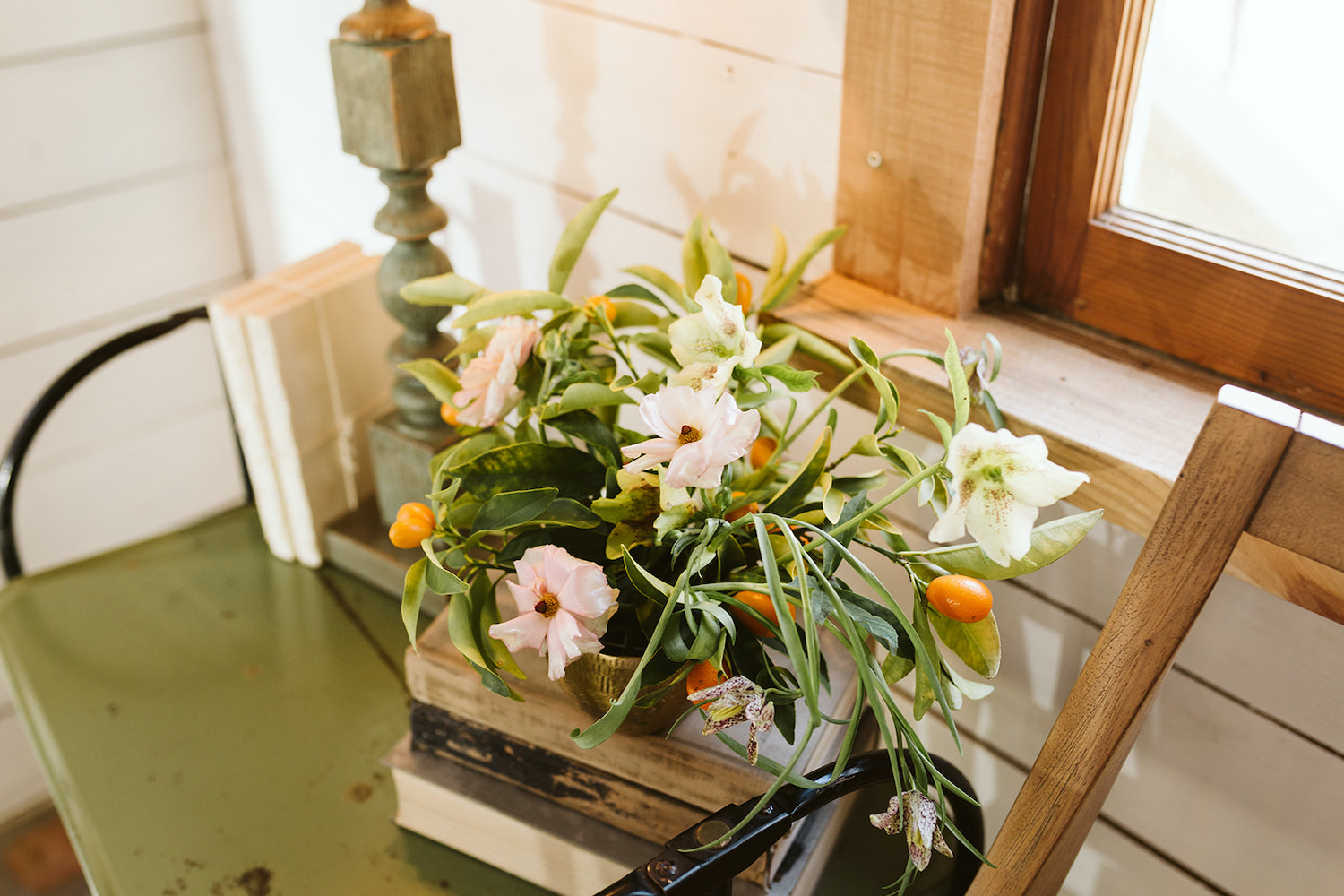 greenery, kumquats, and small flowers in a vase next to white shiplap walls of Oakleaf Cottage