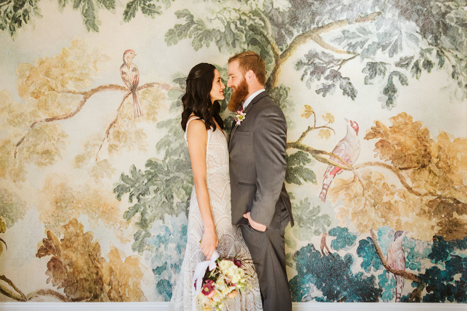 bride stands face-to-face with groom in front of watercolor wallpapered wall at Oakleaf Cottage wedding