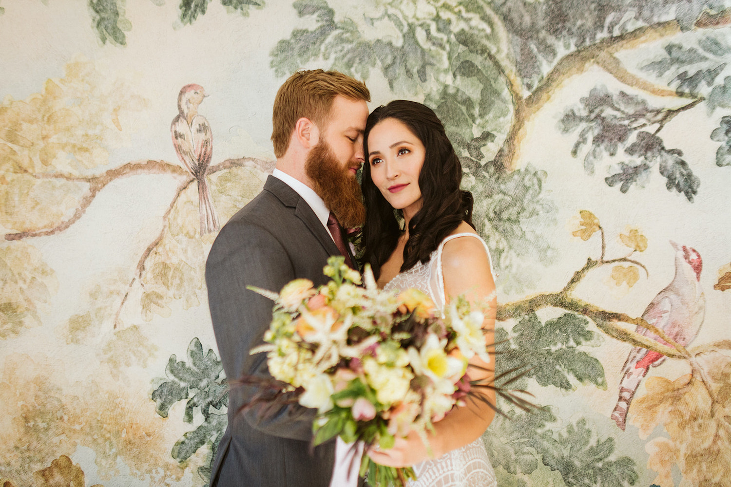 bride stands face-to-face with groom in front of watercolor wallpapered wall at Oakleaf Cottage wedding