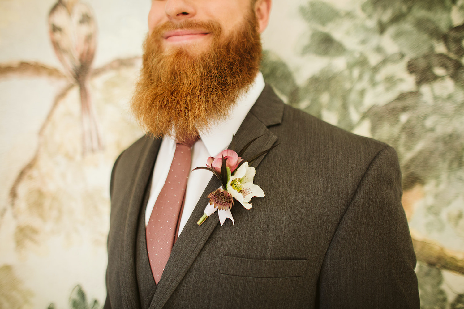 groom's simple boutonniere pinned on his gray suit coat beneath his red beard
