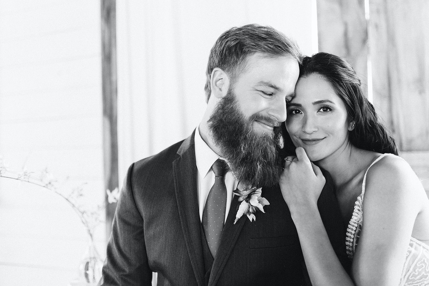 bride and groom sit on a padded bench with her head on his shoulder at Oakleaf Cottage wedding