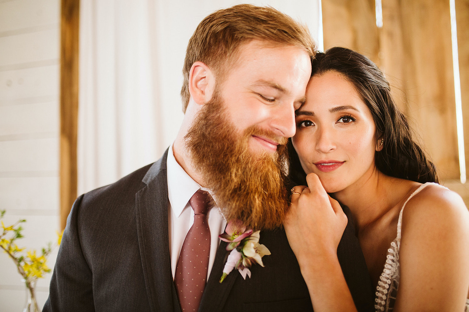 bride and groom sit on a padded bench with her head on his shoulder at Oakleaf Cottage wedding