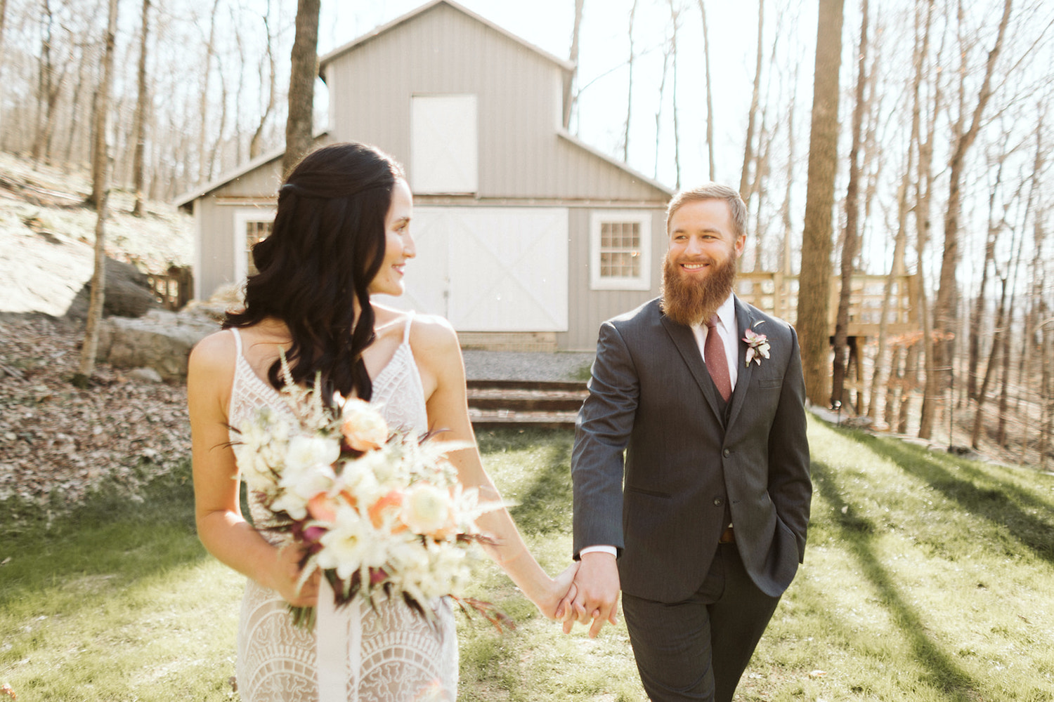 bride and groom hold hands and walk in the lawn in front of Oakleaf Cottage wedding