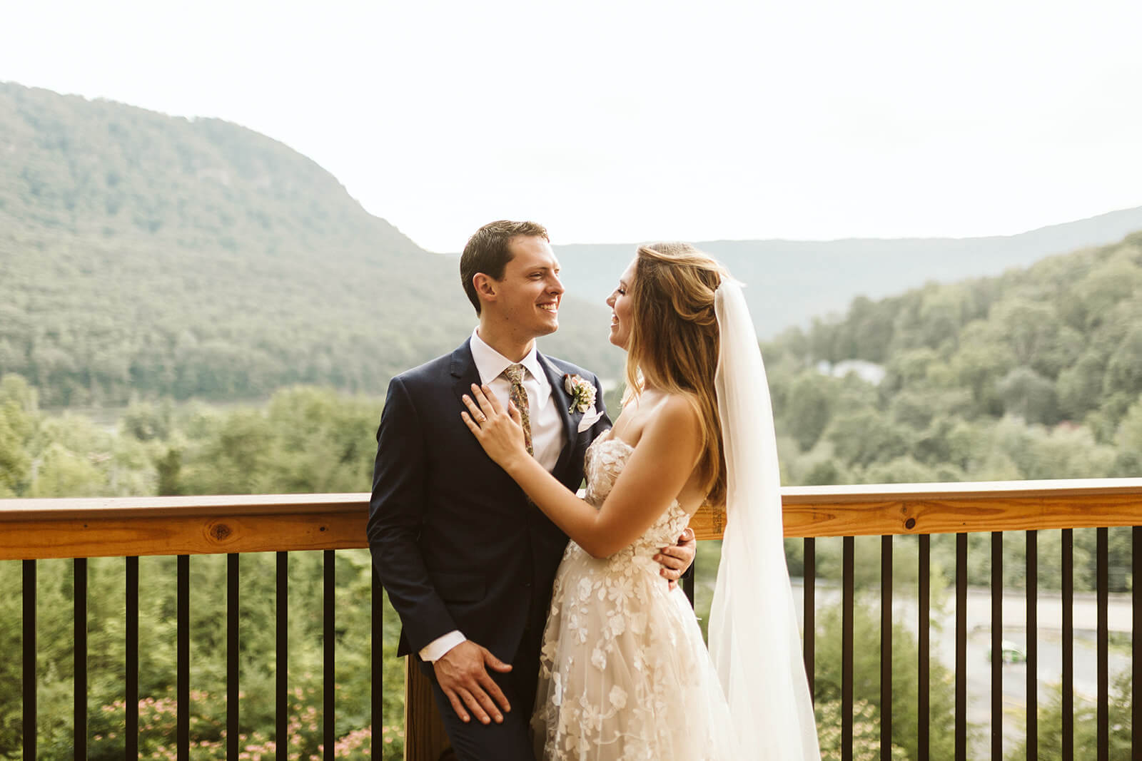 A bride and groom embrace in front of a railing at a mountain wedding venue in Chattanooga.