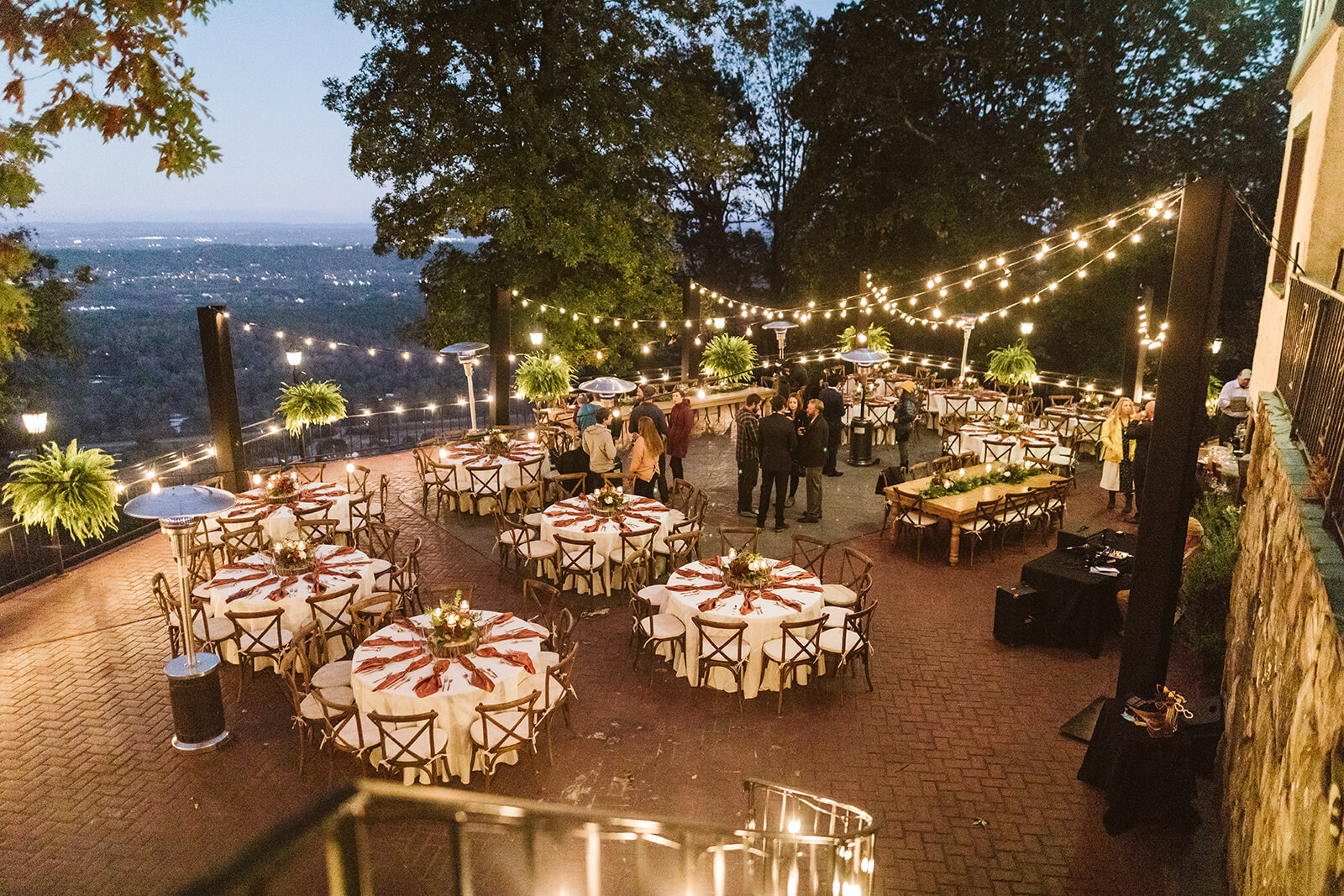 An outdoor dining space at twilight, lit by twinkle lights and candles.