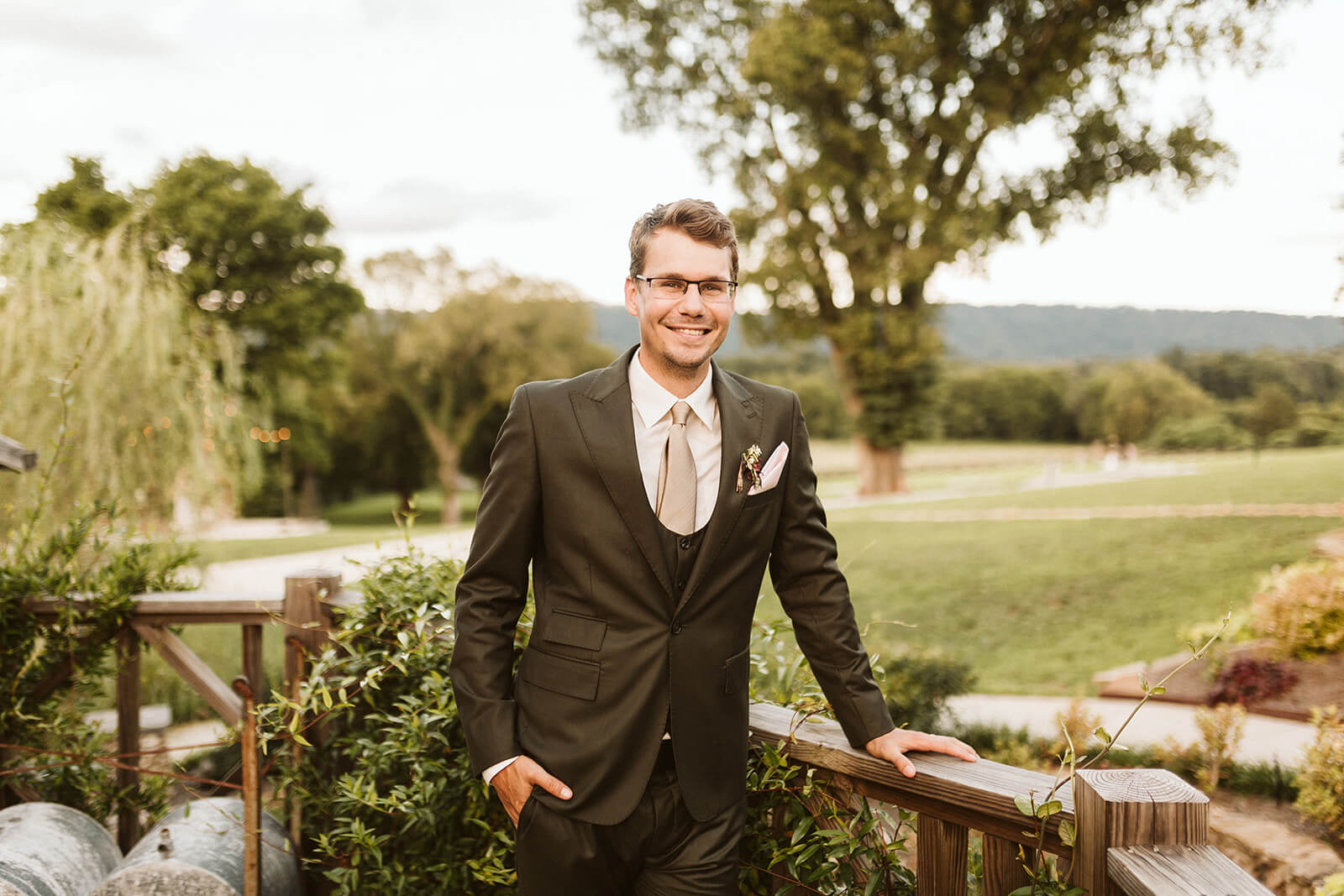 A groom leans on a railing and smiles at a mountain wedding venue in Chattanooga, TN.