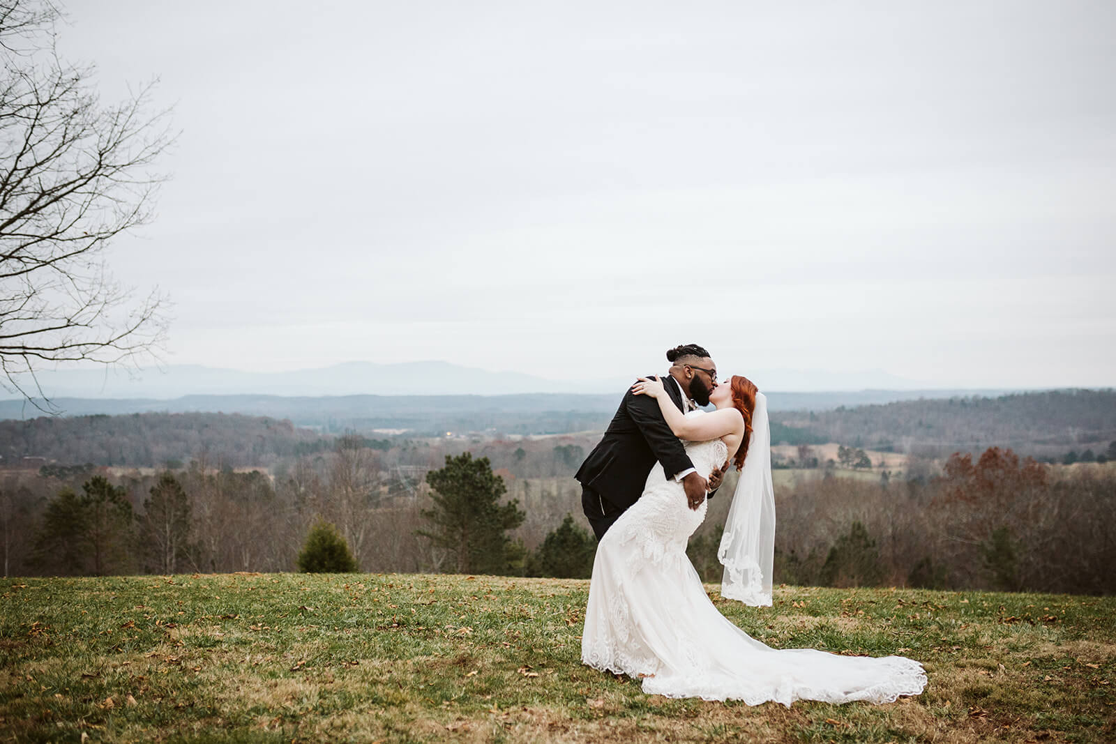 A groom dips his bride into a kiss in front of the Tennessee hills.