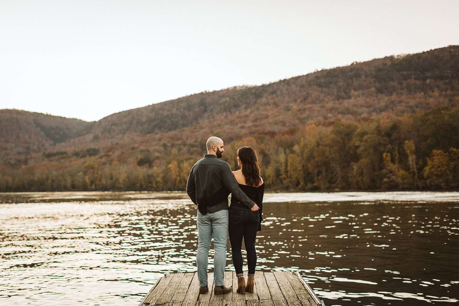 A couple embrace at the end of a dock.