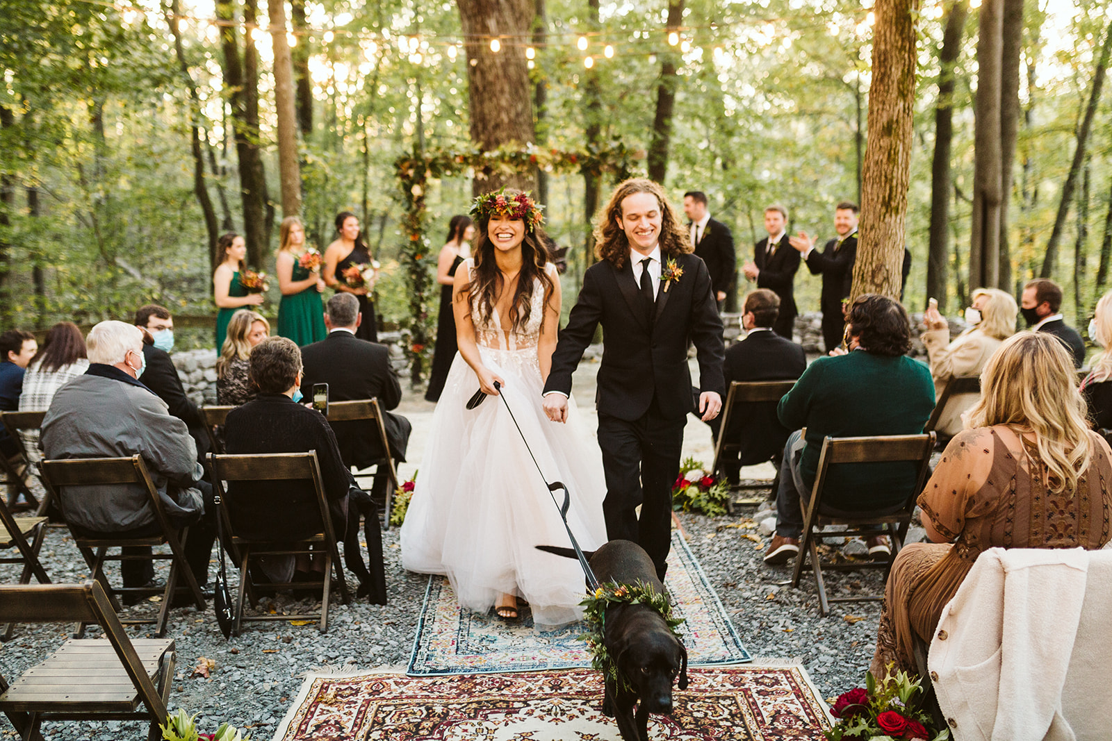 A bride and groom walk their dog down the aisle.