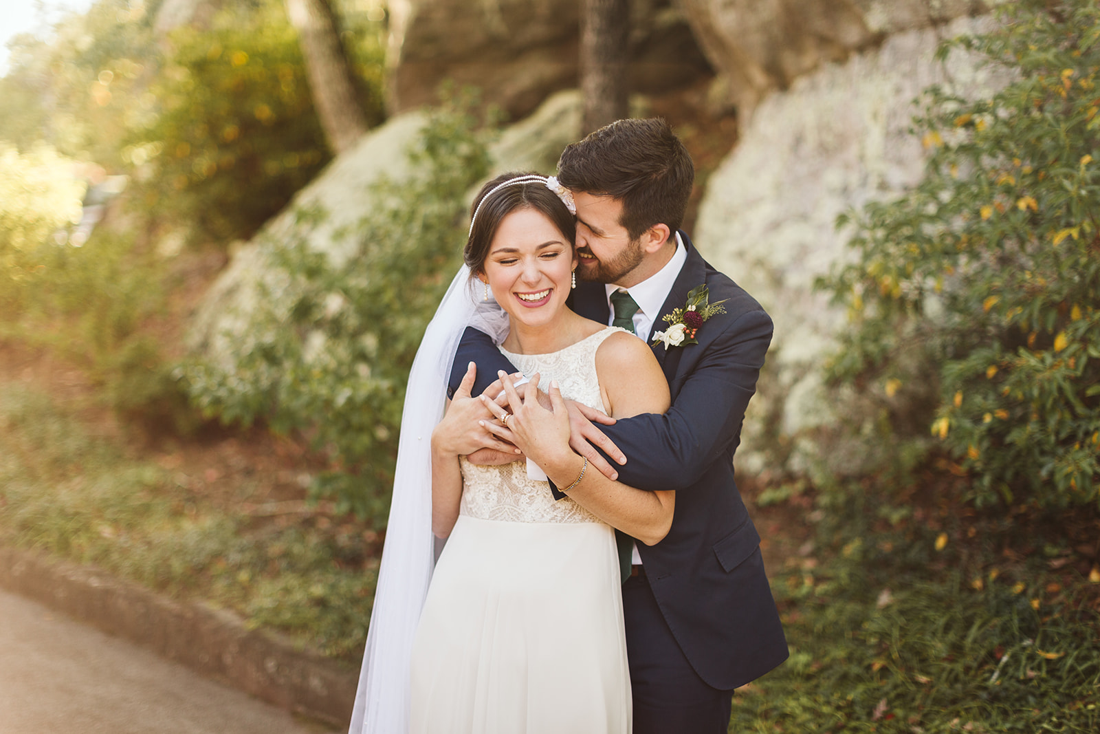 A groom embraces his bride from behind.