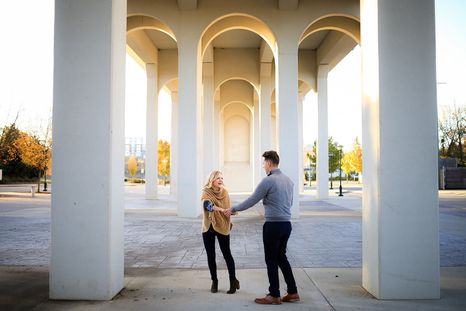 A couple dances under the Market Street Bridge during their engagement photo session in Coolidge Park.