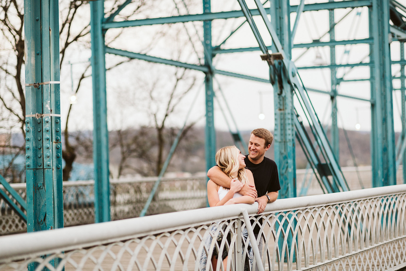 Couple embrace against a railing on a bridge in Coolidge Park.