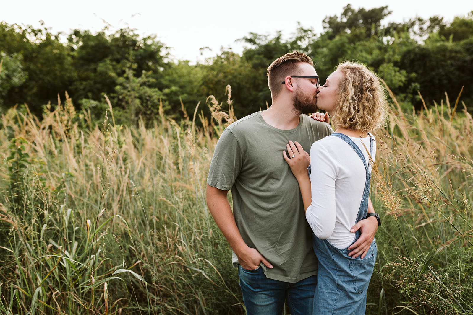 A couple shares a kiss in an overgrown field in Renaissance Park.