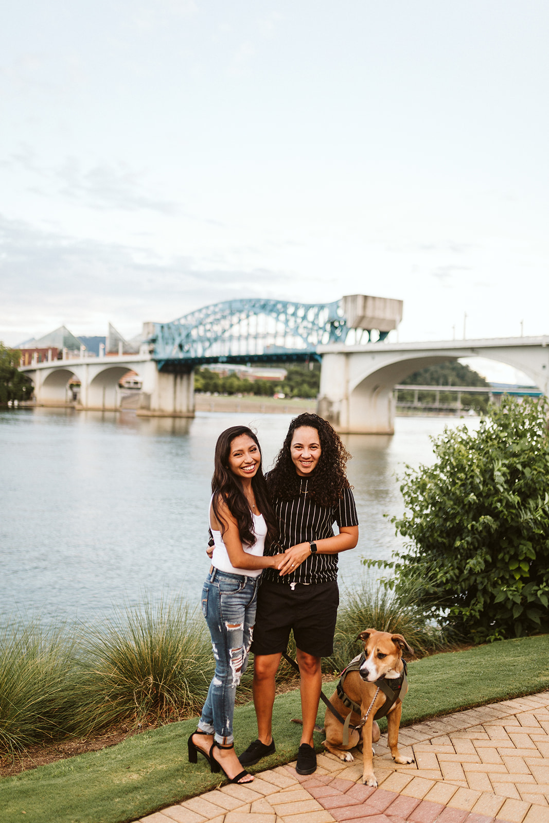A couple poses with their dog during their engagement photos in Coolidge Park.
