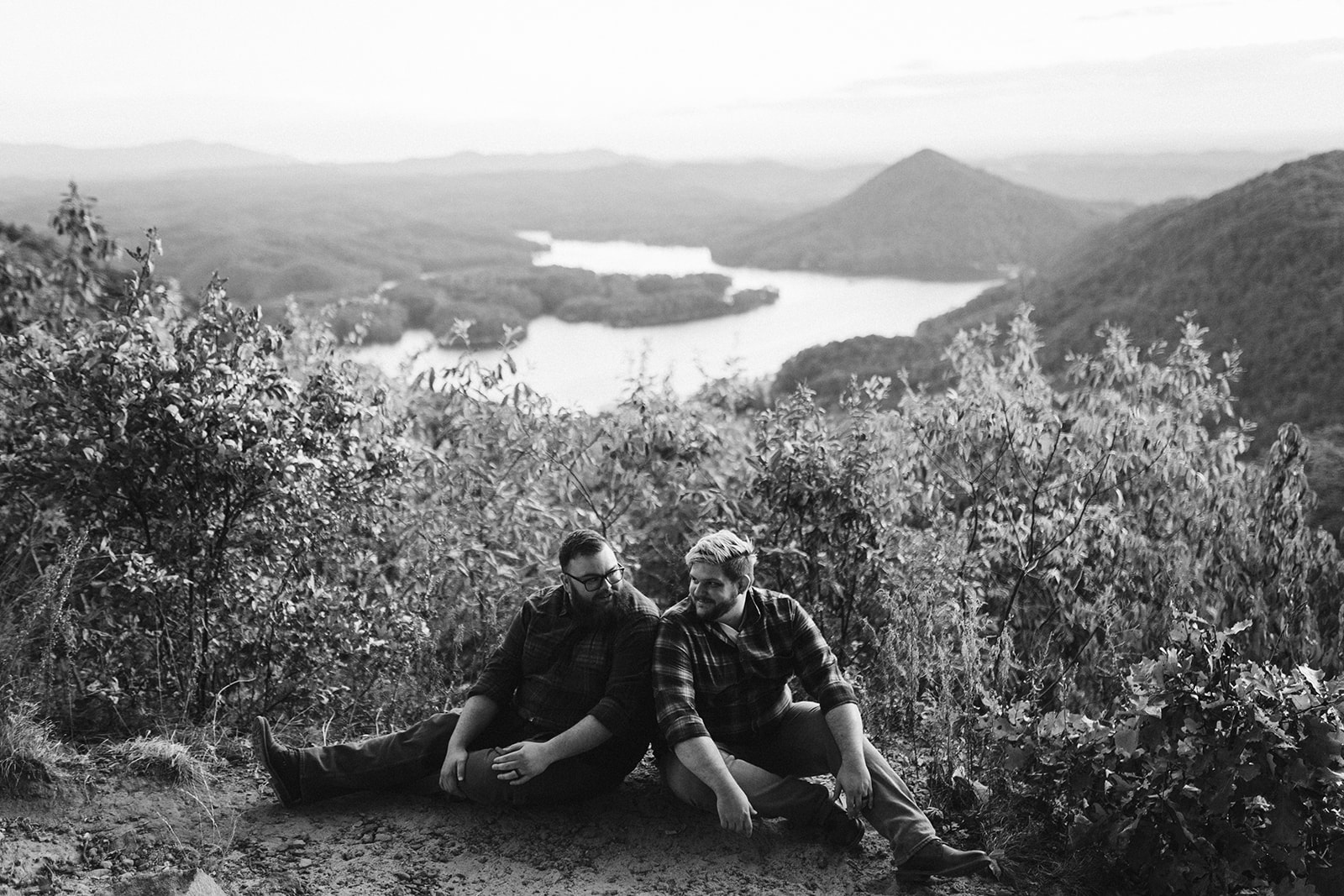 Couple sits together on a mountain overlook during their engagement photo session near Chattanooga.
