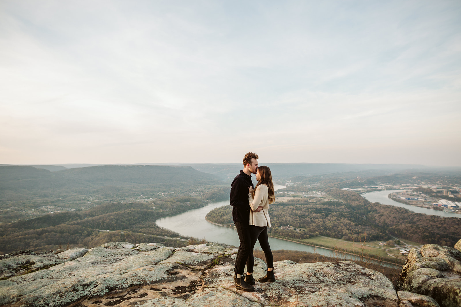Couple embrace during their engagement photo session looking over downtown Chattanooga.