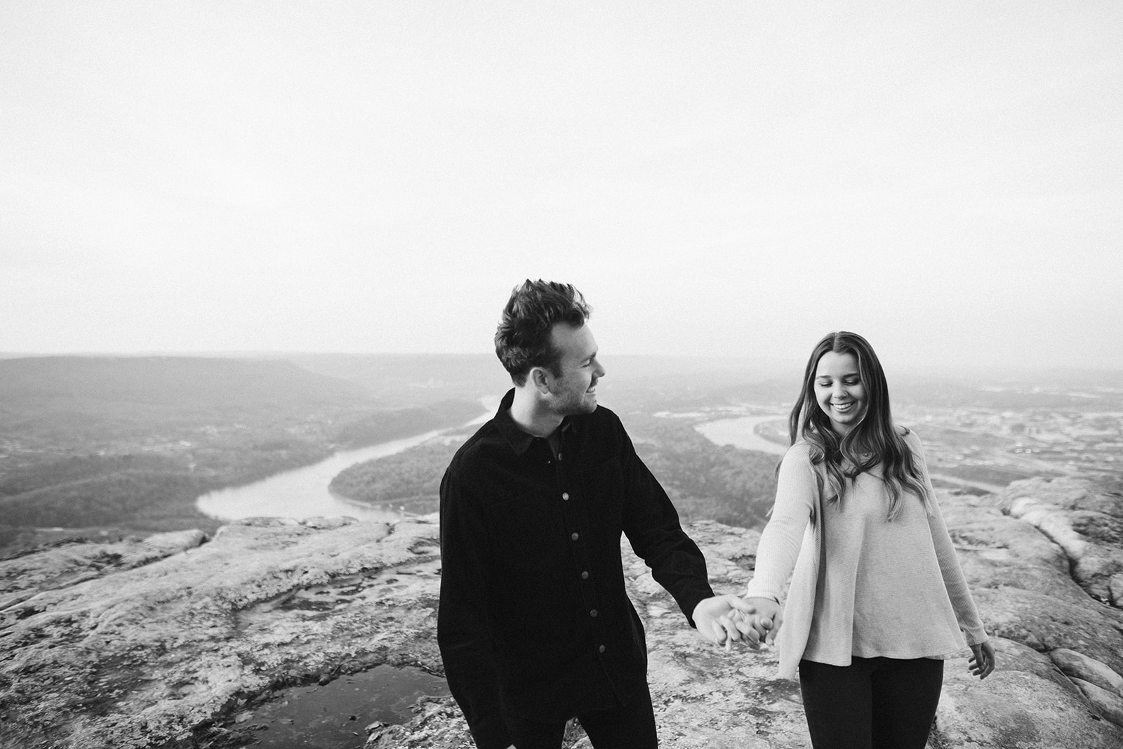 Couple embrace during their engagement photo session looking over downtown Chattanooga.