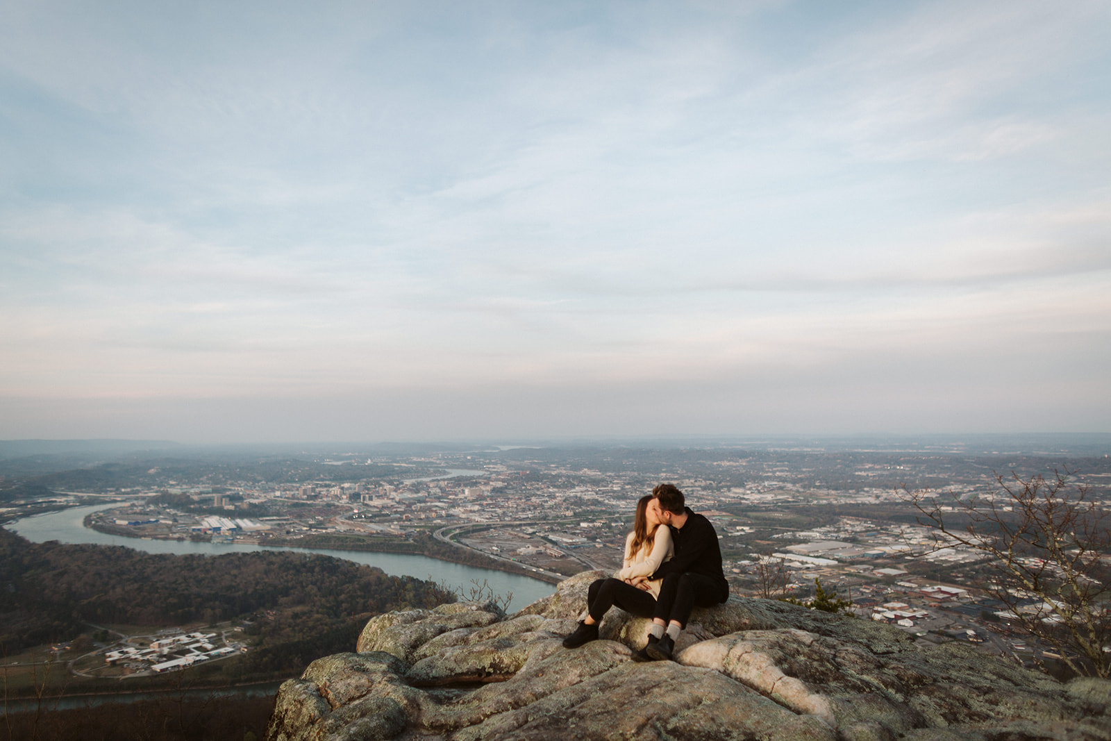 Couple embrace during their engagement photo session looking over downtown Chattanooga.