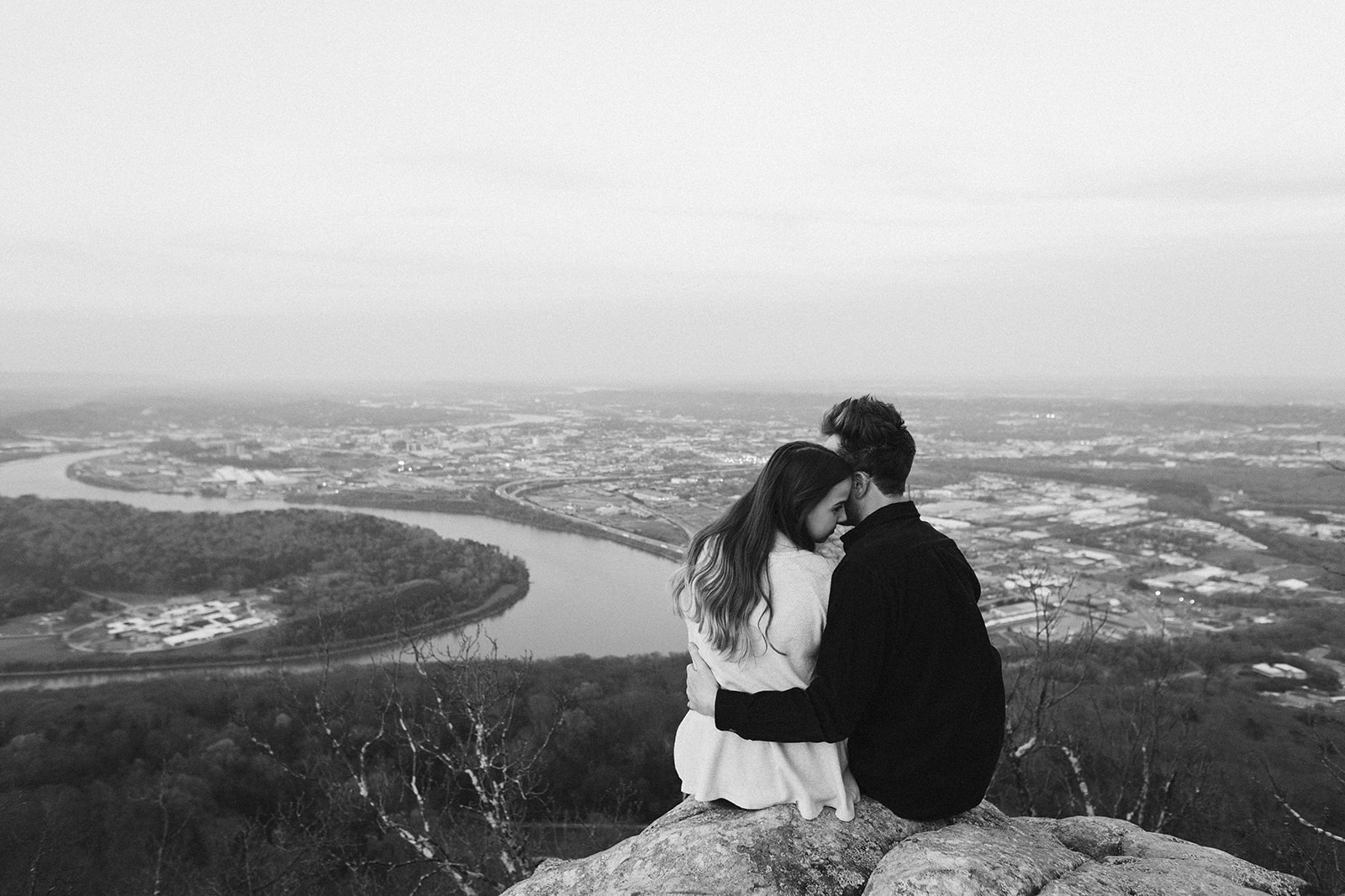 Couple embrace during their engagement photo session looking over downtown Chattanooga.