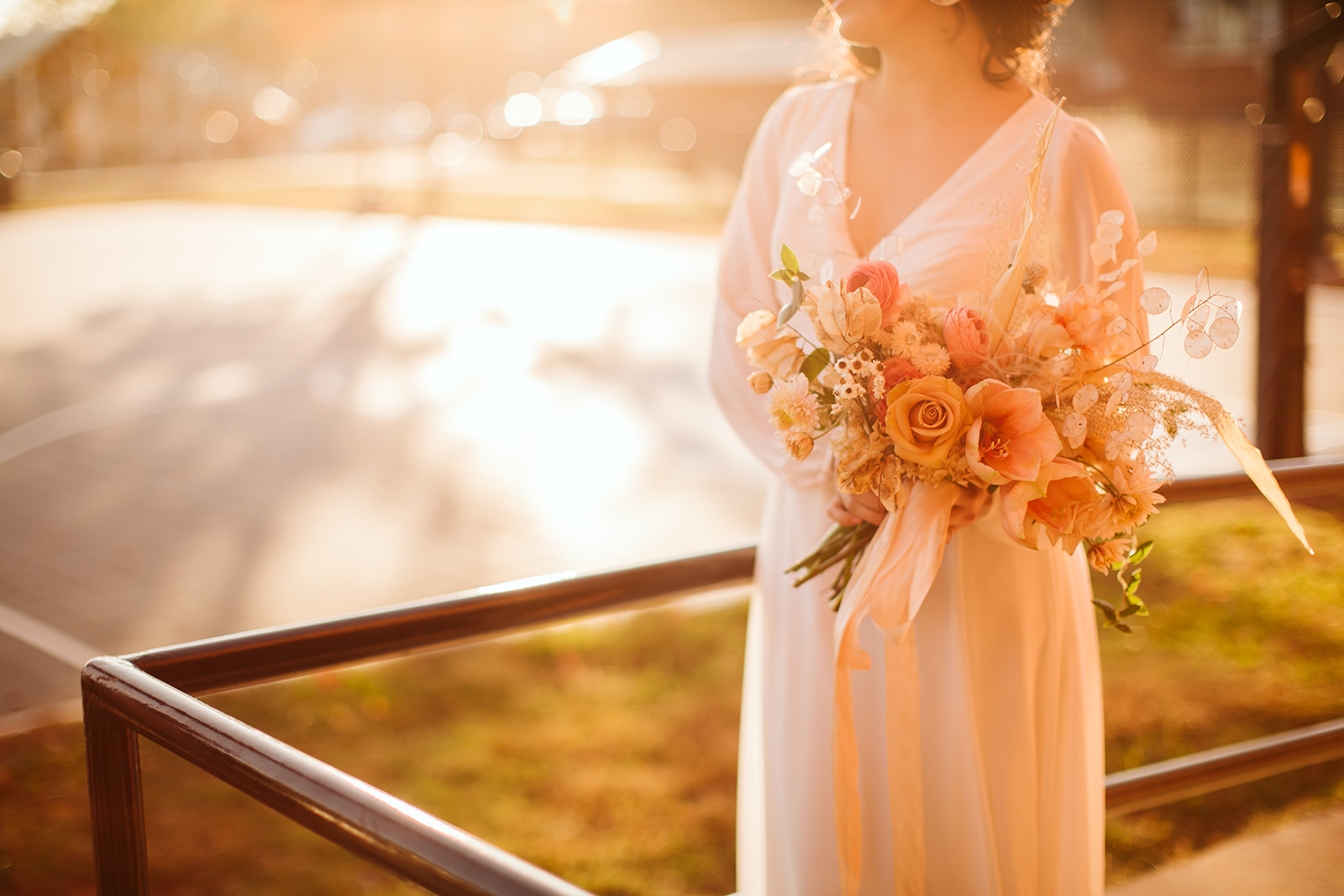 Bride poses in vintage wedding dress with a bouquet of light pink roses.