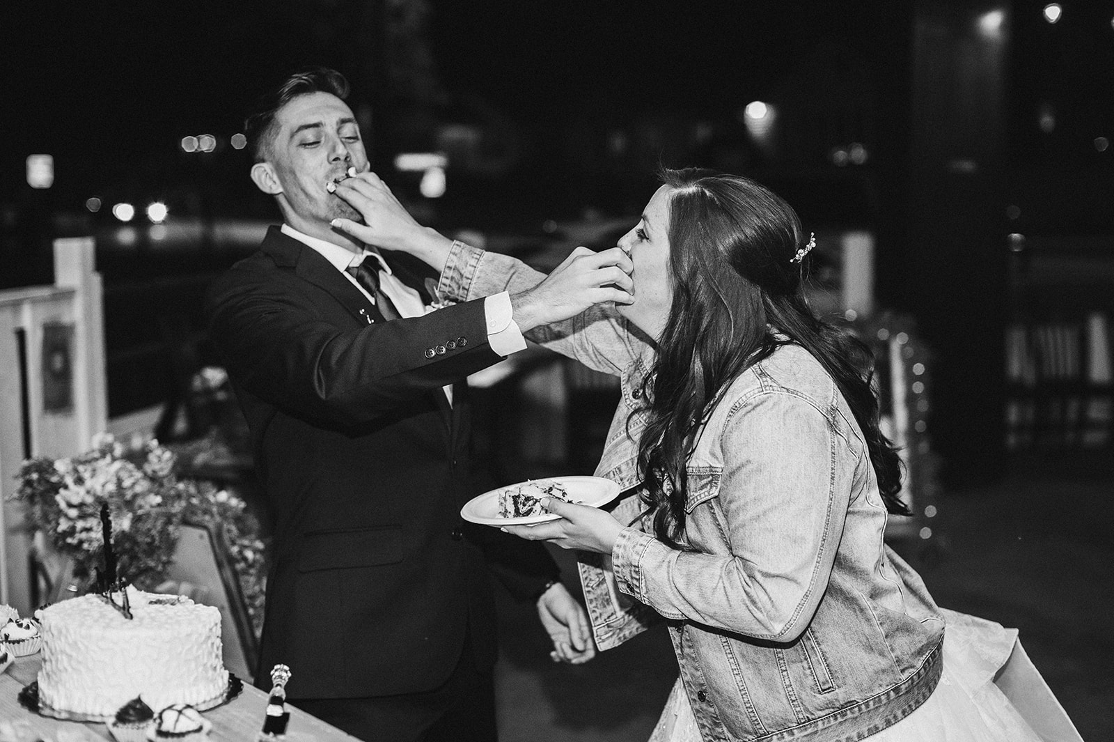 A bride and groom shove wedding cake into one another's faces.