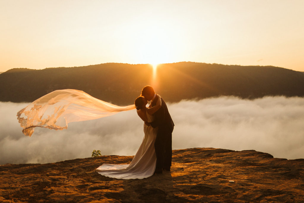 Bride and groom share a kiss under the sunset.