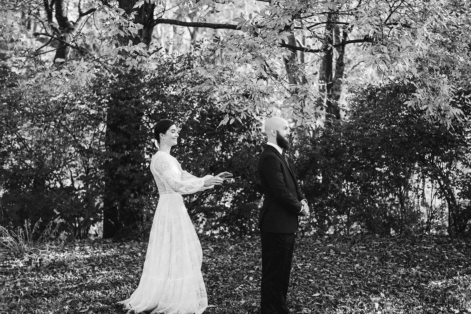 Black and white photo of the bride laughing as she walks towards the groom during their first look outside the Tennessee Riverplace