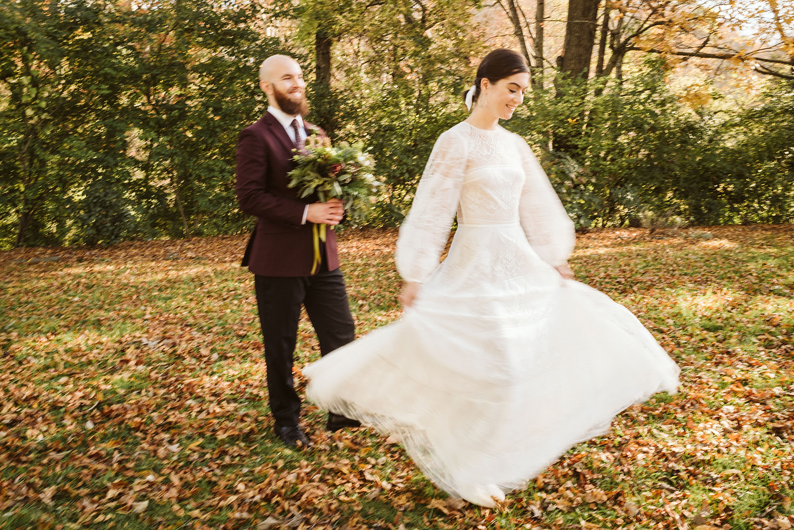 Groom holds brides bouquet as she twirls in the leaves outside their wedding at the Tennessee Riverplace