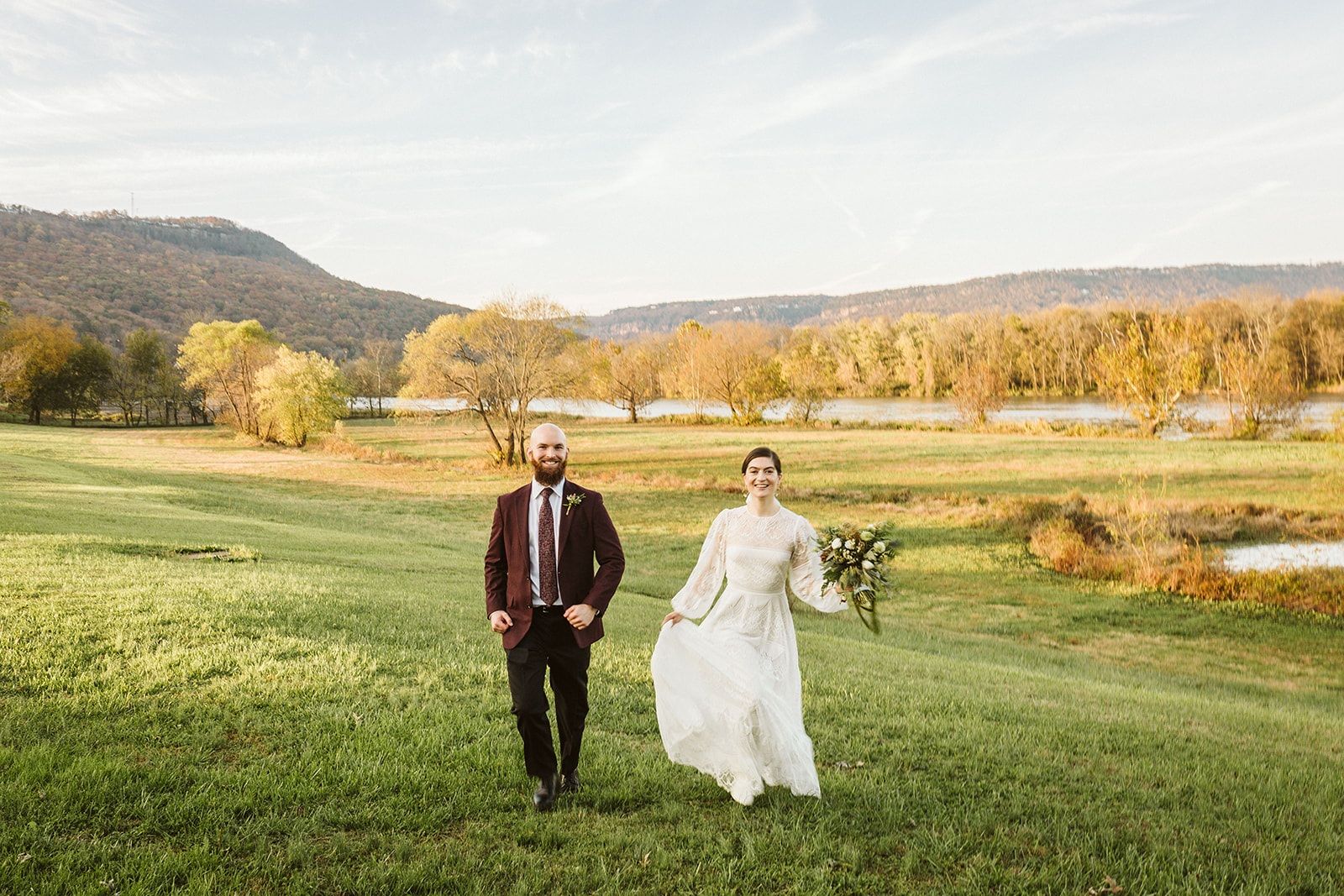 Blurry black and white photo of the bride and groom laughing as they run through a field outside their wedding at the Tennessee Riverplace