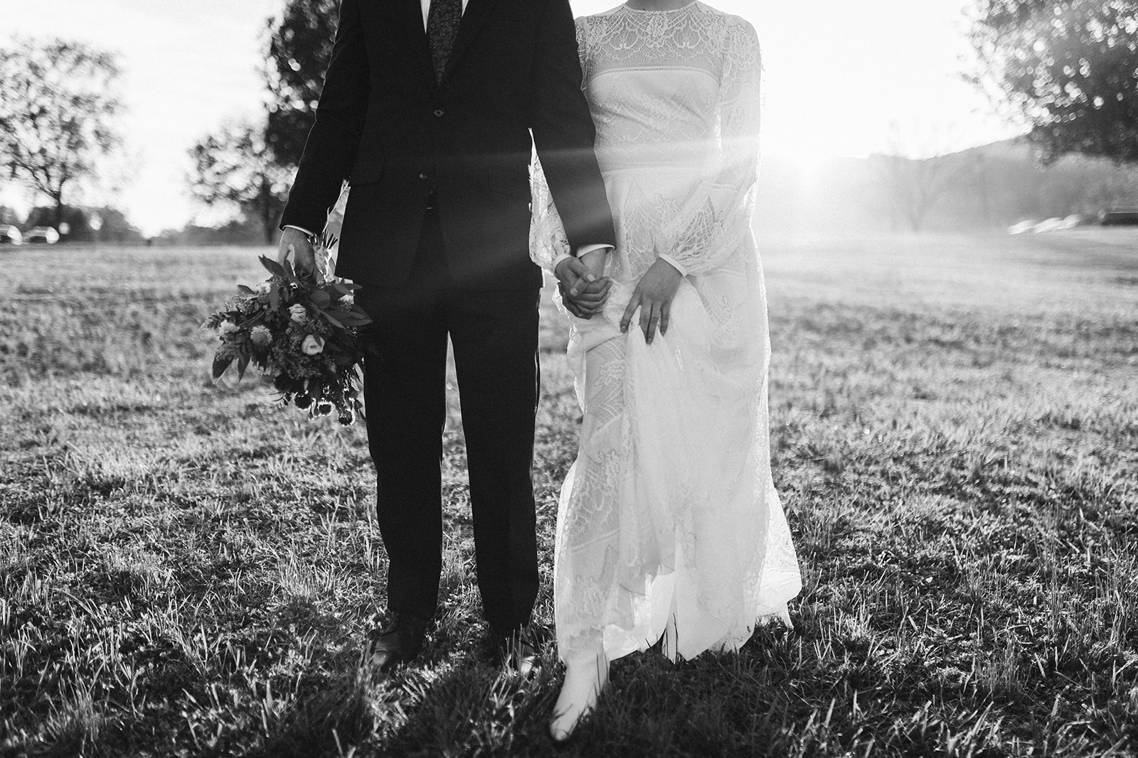 Black and white photo of the bride and groom holding hands as they walk through the Tennessee Riverplace fields