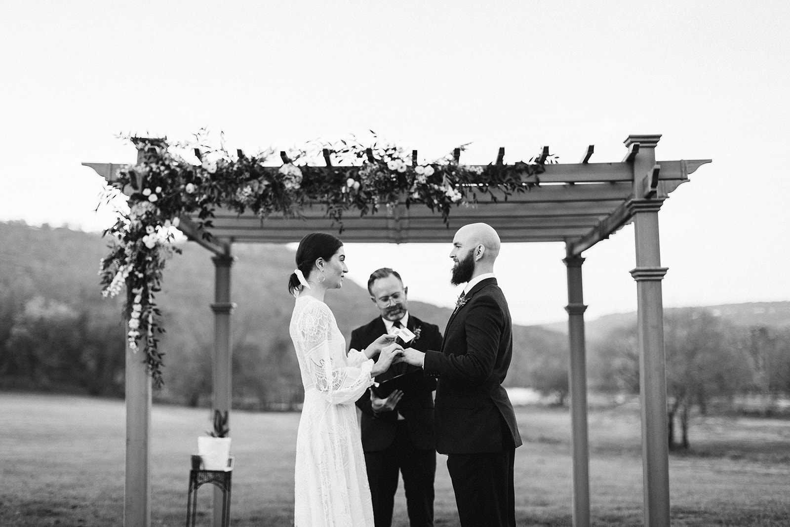 Black and white photo of the bride and groom holding hands and smiling at eachother during their wedding ceremony at the Tennessee Riverplace