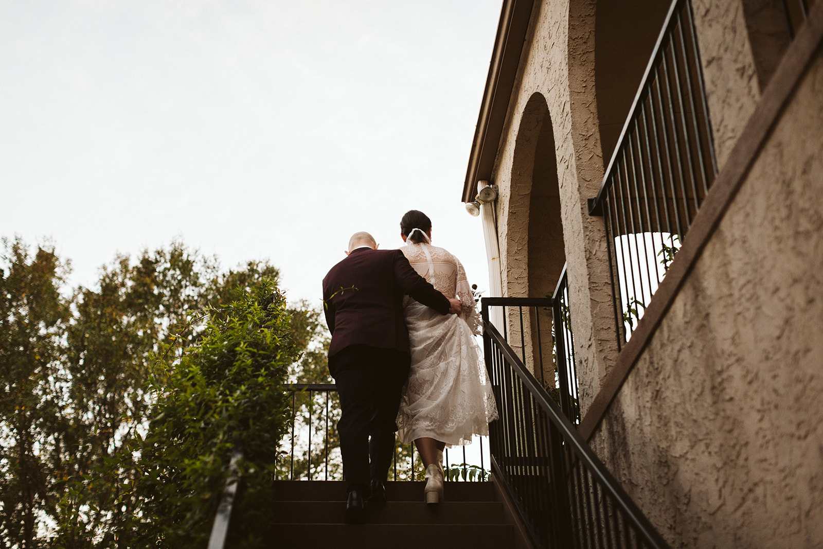 Groom holds brides dress as they walk up the stairs of the Tennessee Riverplace