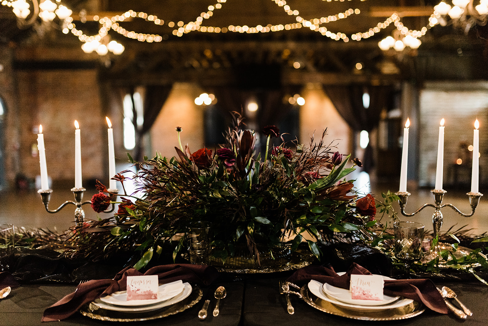A dark, gothic floral arrangement on the head table at a wedding.