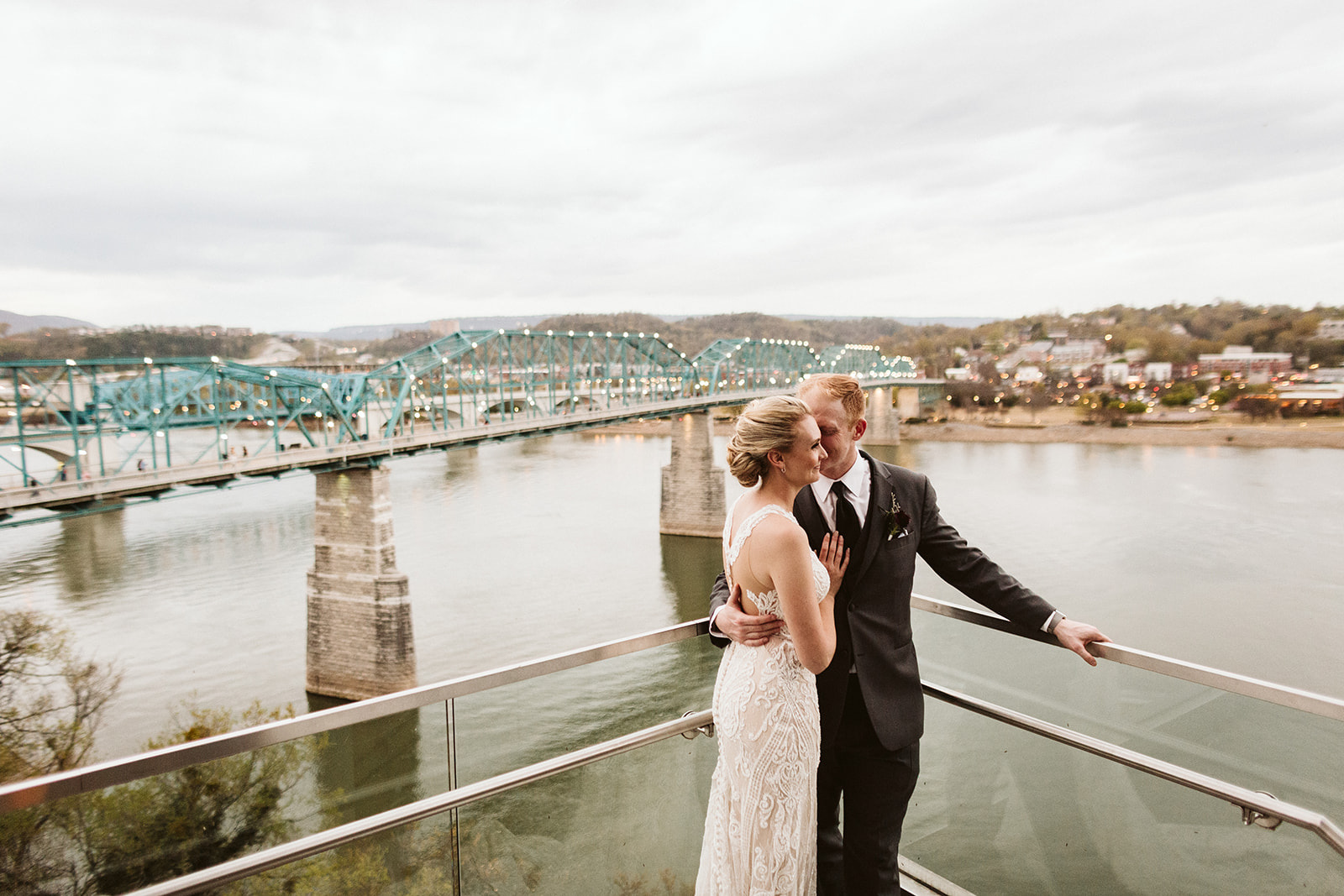 Bride and groom embrace on a bridge overlooking downtown Chattanooga.