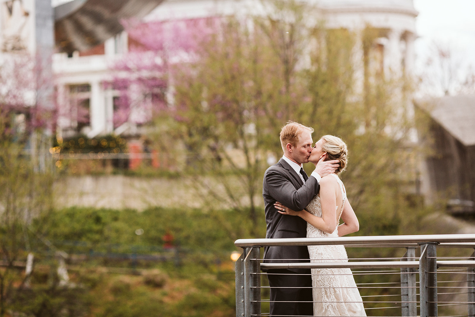 A bride and groom kiss on the walking bridge outside of The Hunter Museum.