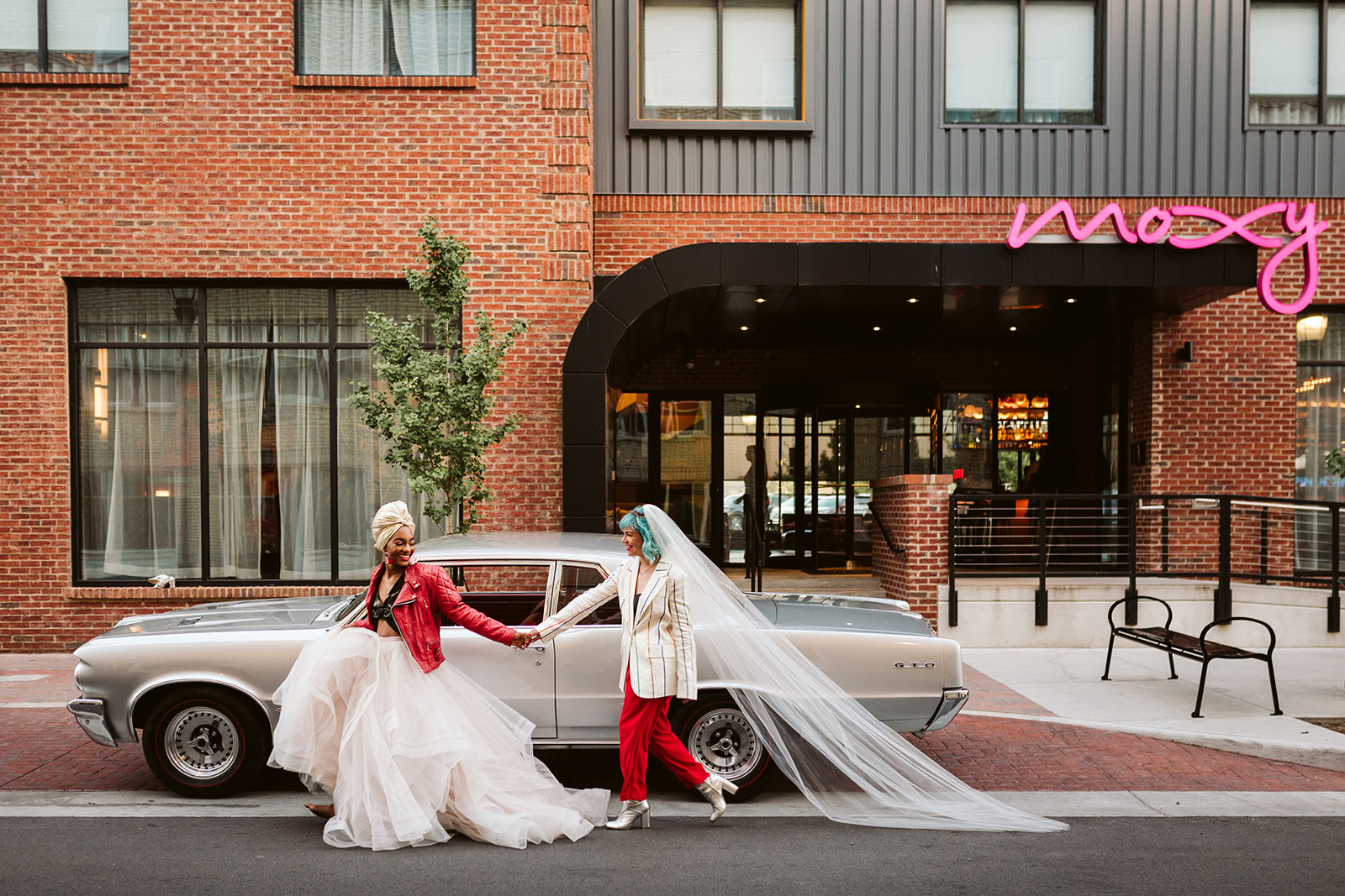 The brides walk hand-in-hand down the street outside Moxy Chattanooga.
