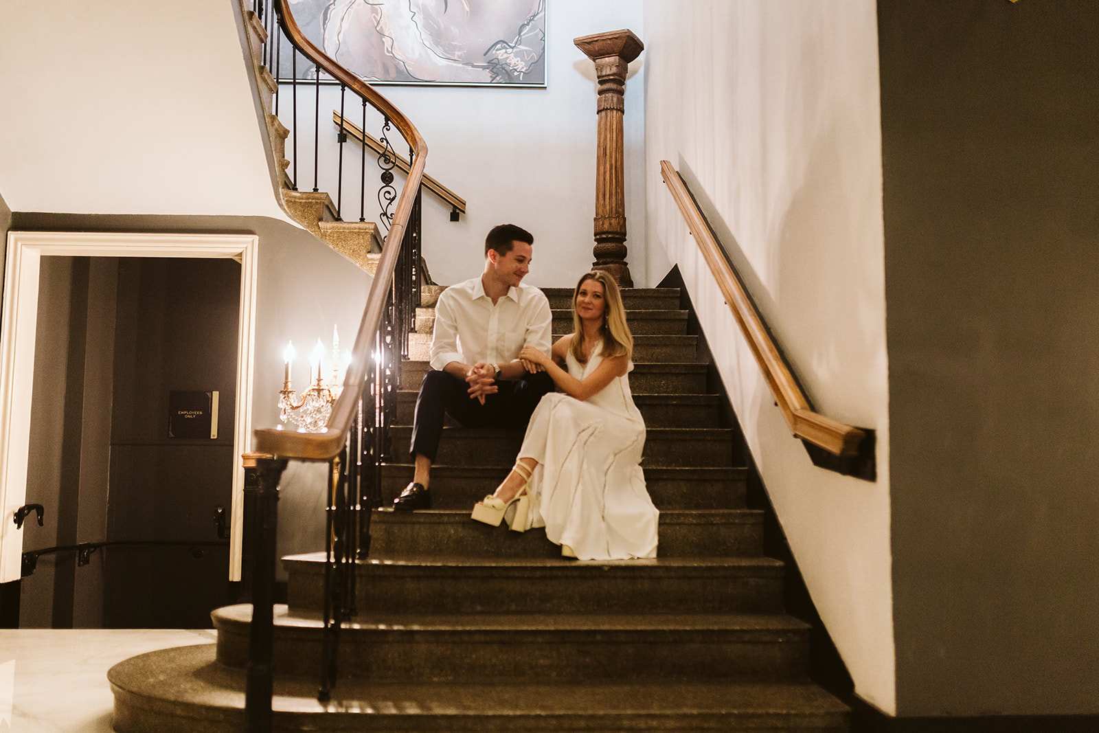 Bride and groom sit together on a winding staircase.