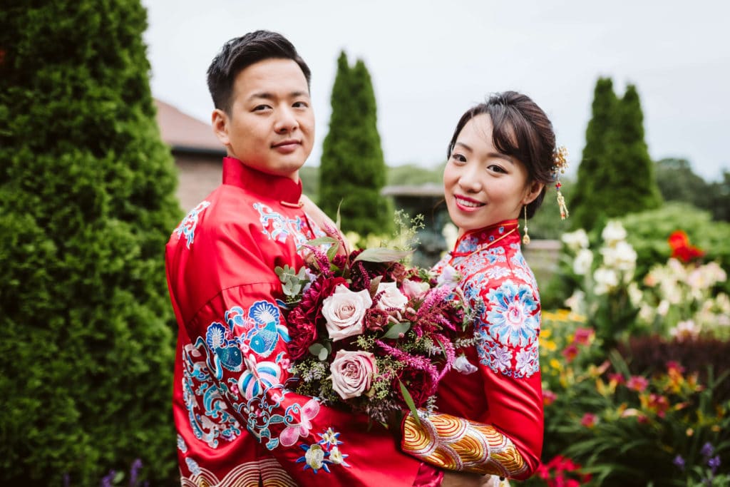 Bride and groom wearing traditional Chinese wedding garments in the gardens of the Oceancliff Hotel.
