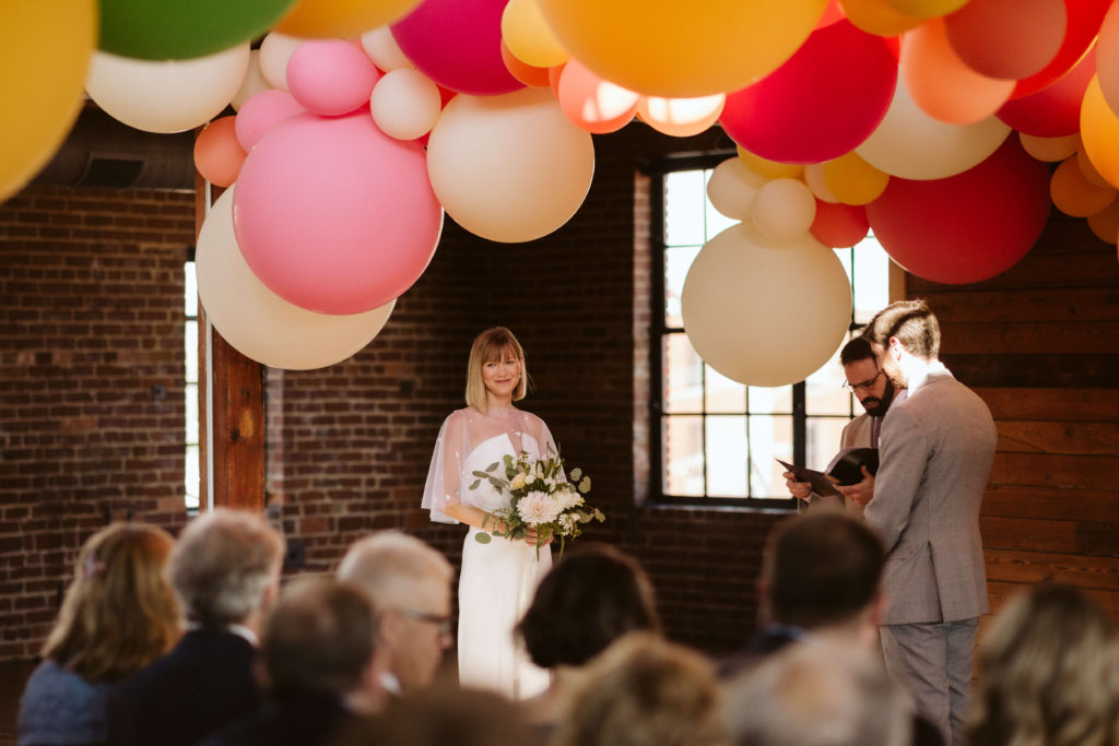 Modern industrial wedding ceremony at the Turnbull Building in Chattanooga with colorful balloon installation. Photo by OkCrowe Photography.