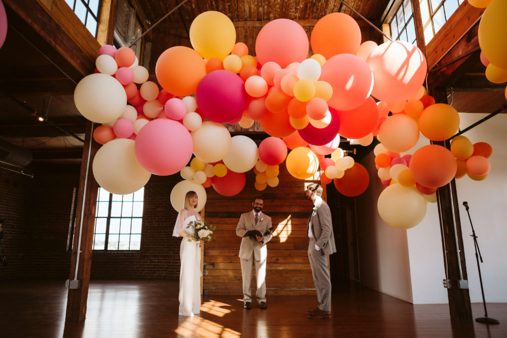 Modern industrial wedding ceremony at the Turnbull Building in Chattanooga with colorful balloon installation. Photo by OkCrowe Photography.