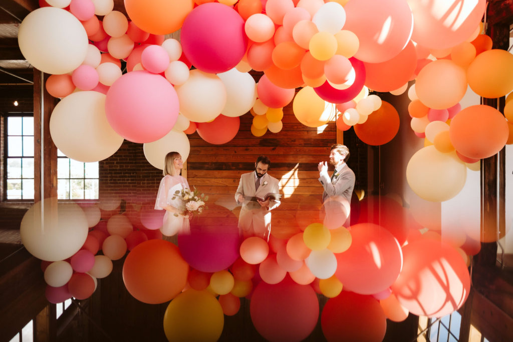 Modern industrial wedding ceremony at the Turnbull Building in Chattanooga with colorful balloon installation. Photo by OkCrowe Photography.